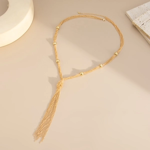 Detail of layered gold fringe necklace with beaded chains and knot design on stone