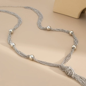 Detail of silver layered chain necklace featuring polished beads and knotted fringe tassels