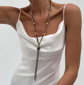 Detail of multi-strand long tassel knot necklace with gold beads on elegant silk dress