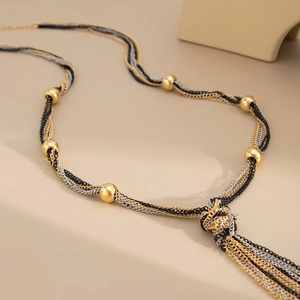 Detailed shot of triple-tone mixed chain necklace with metallic beads and knot tassel design