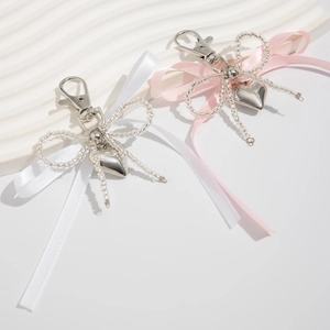 Détail d'un bijou de sac nœud en satin avec perles et pendentif cœur argenté