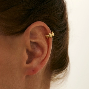 Detailansicht einer goldfarbenen C-Ohrmanschette mit Hammerschlag-Optik am Ohr getragen
