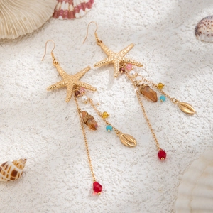 Details von böhmischen Seestern-Ohrringen mit bunten Perlen auf weißem Sandstrand