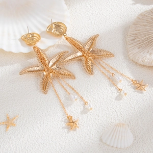 Detail von Gold-Seestern-Ohrringen mit Perlen-Quasten auf Meeresstrand-Deko