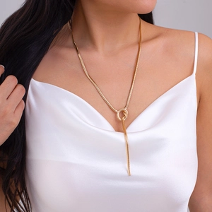 Close-up of golden flat snake chain necklace with a knotted tassel design on a model