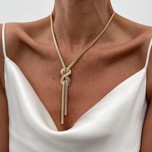 Elegant gold-tone flat snake bone chain necklace with a stylish knot and tassel pendant