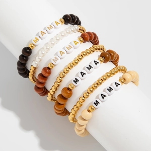 Detail of five bohemian wood beaded bracelets set with MAMA letter beads on white stand