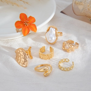 Detail van zeven gouden ringen met een oranje bloem en een barokke parel accent