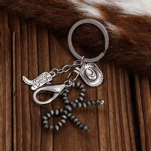 Détail du porte-clés cowboy vintage avec bottes, chapeau et perles en métal gris
