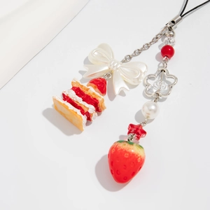 Détail d'un porte-clés gâteau à la fraise avec nœud blanc et perles fantaisie