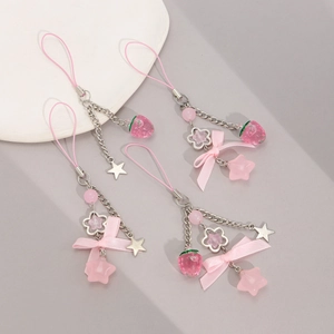 Macro detail of pink strawberry pendant and silk bow charms for phone and bag decor