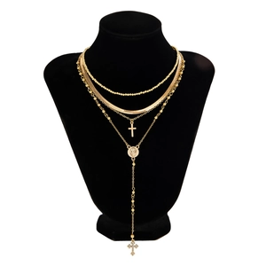 Detalle de collares dorados en capas con cruces y perlas en un busto de exhibición negro