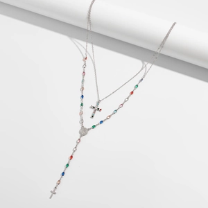 Dettaglio della collana argentata a strati con cristalli colorati, medaglia di Maria e croci