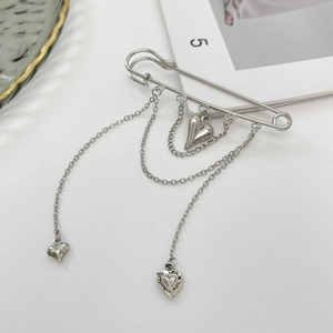 Detail of silver safety pin brooch with multi-layered chains and heart pendants
