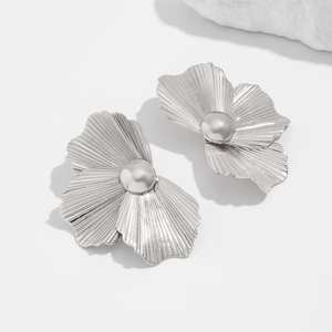 Dettaglio di orecchini a fiore in metallo argento con texture plissettata e sfera