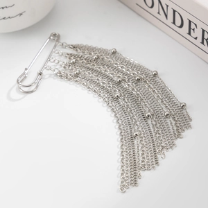 Dettaglio spilla da balia argento con nappe metalliche a strati e perline fini