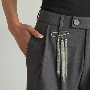 Spilla da balia in metallo argento con nappe a catena lunga su pantaloni grigi