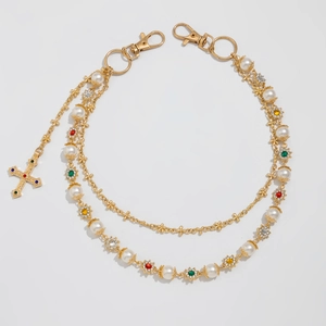 Detail of multi-layer gold pant chain with pearls and colorful rhinestone cross pendant