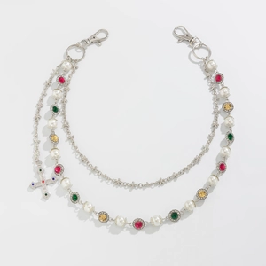 Detail of multi-layer silver pant chain with pearls, colorful gems and cross pendant