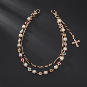 Detail of gold chain with pearls, colorful rhinestone flowers and cross pendant