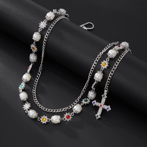 Detail of vintage layered chain with pearls and a rhinestone cross pendant on black