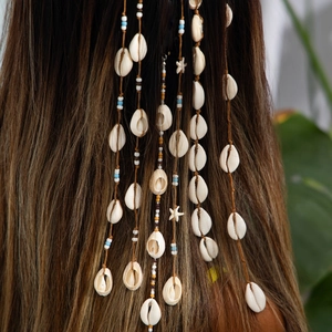 Détail de bijoux de cheveux bohèmes à perles et coquillages sur cheveux tressés