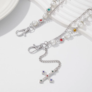 Detail of silver chain with colorful rhinestone cross pendant and faux pearls