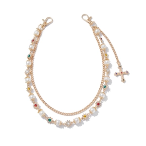 Close-up of golden multi-layer chain with colorful rhinestones, pearls and cross pendant