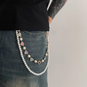 Detail of multi-layered gold chain with pearls and colorful heart stones on jeans