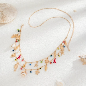 Multilayer gold ocean chain necklace with sea turtle and shell pendants on beach sand