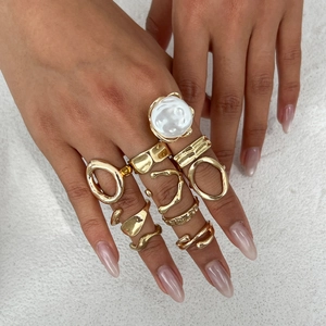 Macro view of gold stacking rings featuring irregular textures and faux pearl detail