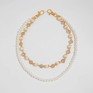 Detail of double-layer pearl chain with gold flower charms and rhinestone crosses