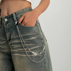 Detail of silver layered waist chain with flame pendants and punk metal links on jeans