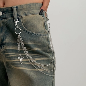 Detail of silver multi-layer metal trousers chain with cross pendants on denim jeans