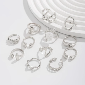 Flat lay of 12 silver-tone rings with twisted, irregular, and minimalist smooth designs