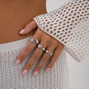 Détail macro du bracelet modulaire en métal argenté poli de forme fluide sur un mannequin