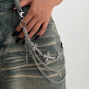 Detail of multi-layered gothic metal waist chain with silver cross pendants on denim