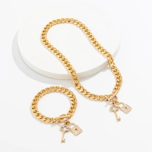 Detail van gouden Cubaanse ketting met sprankelende hartslot en sleutel hanger set
