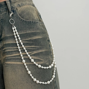 Detail of double-layer faux pearl waist chain with silver lobster clasp on blue denim jeans
