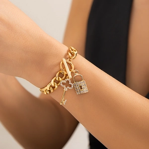 Detail van gouden Cubaanse schakelketting met sprankelende hart-sleutel en slot hangers