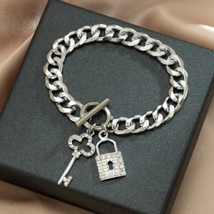 Detail van de zilveren schakelketting met hartvormige sleutel en slot hanger met kristal