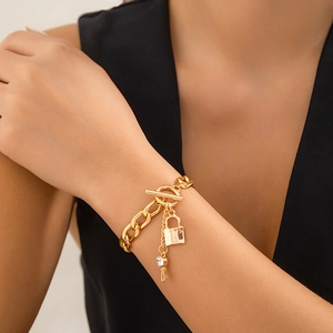 Detail van gouden schakelketting met gepolijst slot en kristallen sleutelhangers op de nek