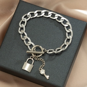 Detail van een zilveren grove kettingarmband met OT-sluiting en hangers in de vorm van sloten