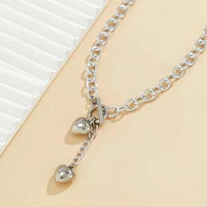 Detail van een zilveren hartjesketting met grove schakels en klassieke OT-sluiting