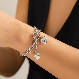 Detail van zilveren hartjesarmband met T-sluiting om de pols van het model