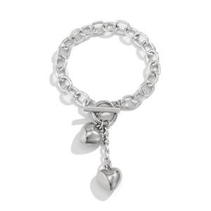 Detail van zilveren schakelarmband met T-sluiting en hangende metalen hartvormige hangers