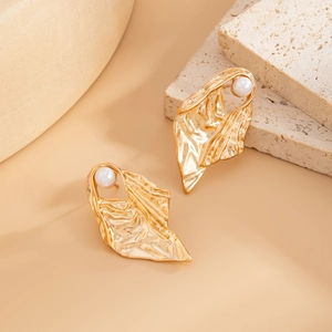 Detail of gold floral heart earrings with wrinkled texture and pearl accent