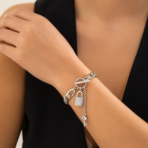 Detail van de zilveren dikke ketting met diamantbezet slot en sleutelhanger hangers