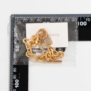 Detail van de gouden ketting met strass slot hanger naast een liniaal voor maataanduiding