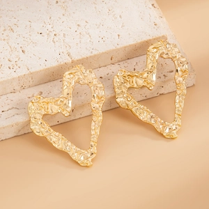 Macro detail of gold heart earrings with irregular crinkled liquid metal texture